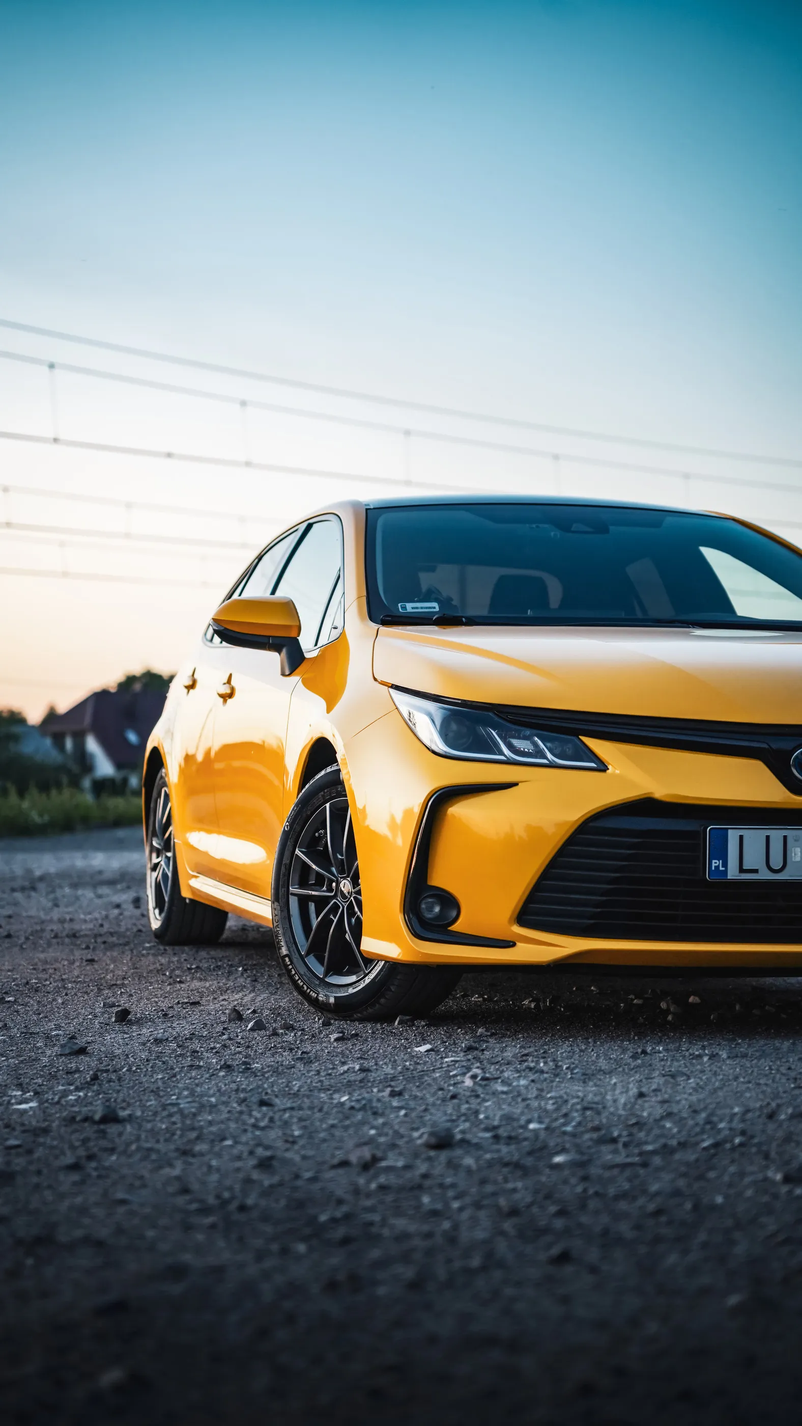 Przód żółtej Toyoty Corolli z bliska, z niskiej perspektywy